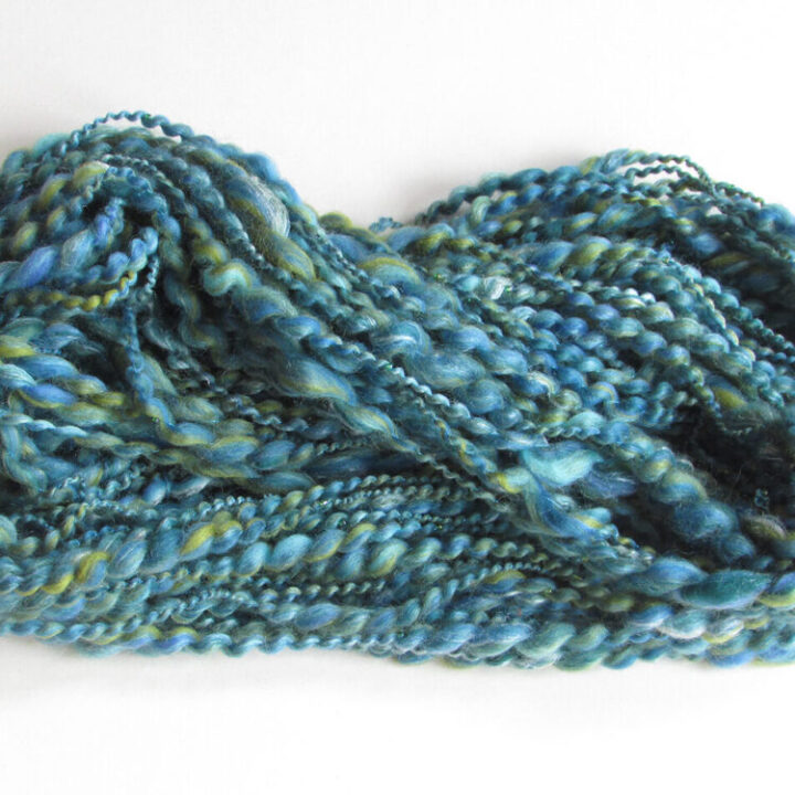A skein of hand spun beaded yarn in the Polzeath Breeze colourway of blues and greens.