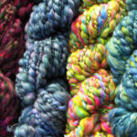 Four skeins of brightly coloured hand spun, beaded yarn