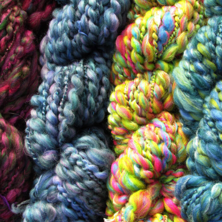 Four skeins of brightly coloured hand spun, beaded yarn