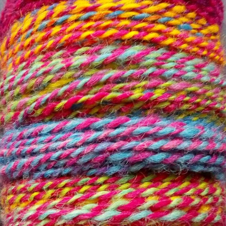 Close up view of a bobbin of brightly coloured hand dyed, hand spun Cornish Romney yarn