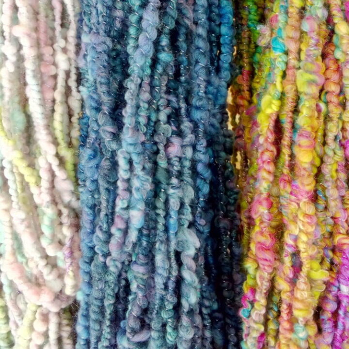 Three skeins of corespun yarn. One in pastel colours, one in blues and lilacs and one in bright neons.