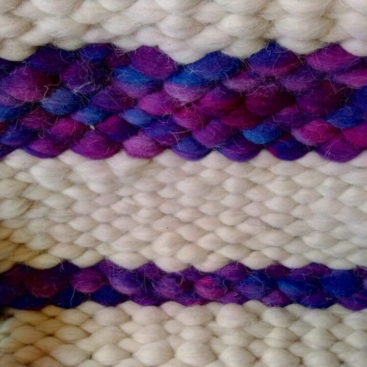 A piece of peg loom weaving in white with two purple stripes.