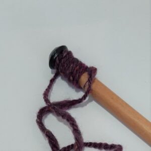 A knitting needle being used as a yarn gauge