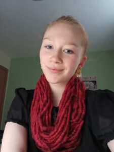 A young woman wearing a red and black handspun cowl