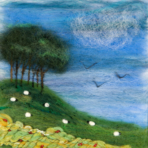 Example of a needle felt picture depicting a stand of trees on a hill to the left with sheep grazing on the hill. Foreground is a hedgewall made of yarn with beads sewn in. For felting workshops in North Cornwall. 
