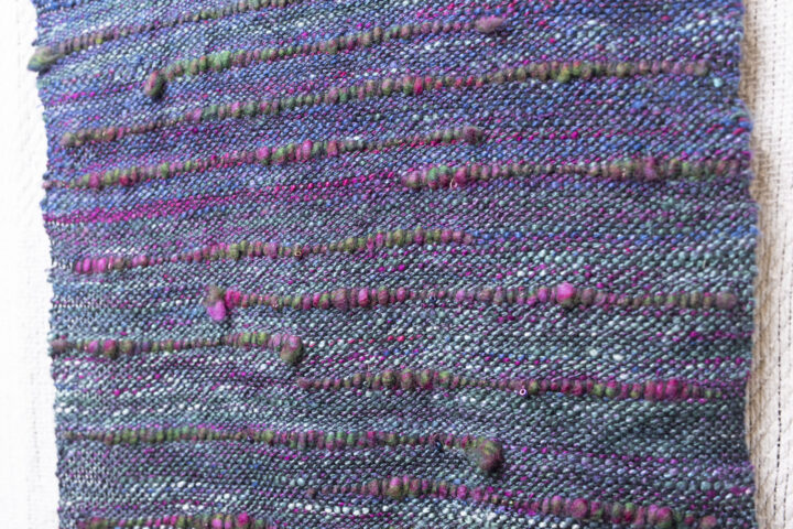 A close up of the handwoven silk scarf showing the textured hand spun yarn inclusions.