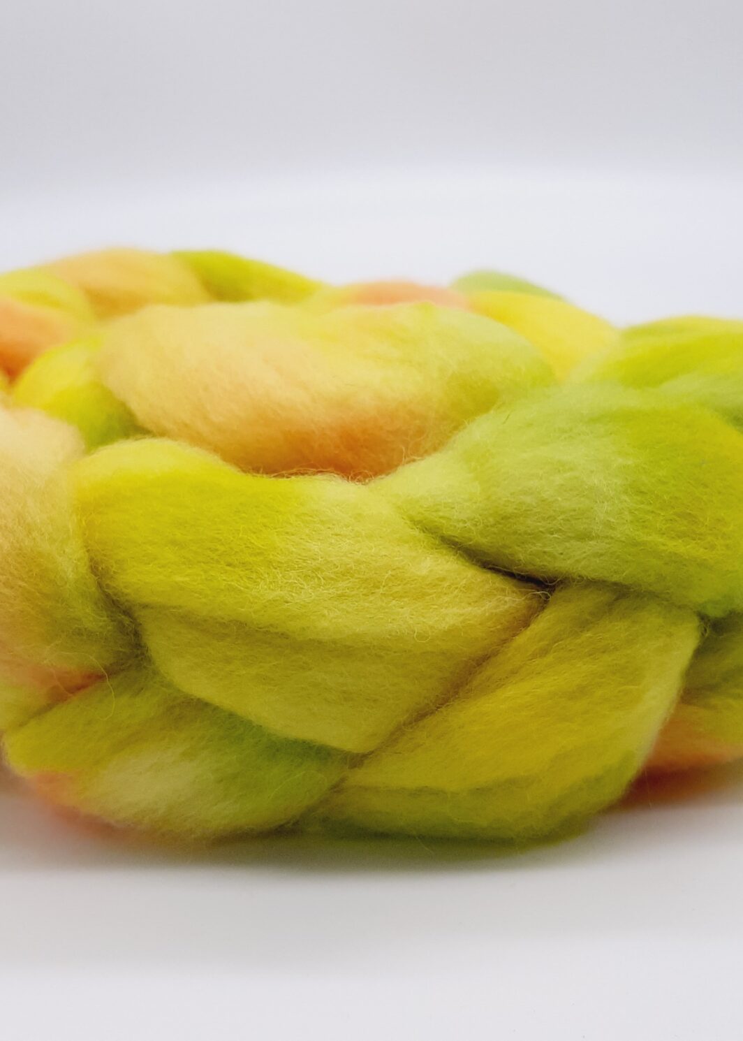 A close up view of a braid of Bluefaced Leicester fibre hand dyed in yellow, green and orangey red.