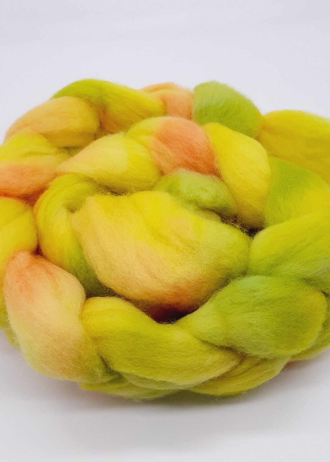 Close up image of a braid of Bluefaced Leicester fibre hand dyed in yellow, green and orangey red.