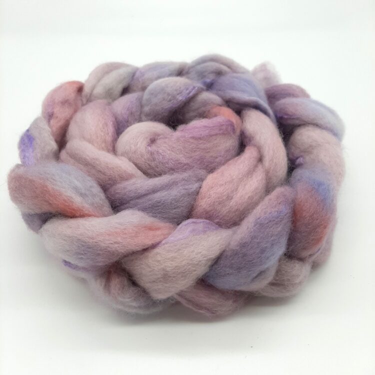 close up view of a braid of hand dyed bluefaced leiceter and silk fibre in shades of purple with a rosy blush