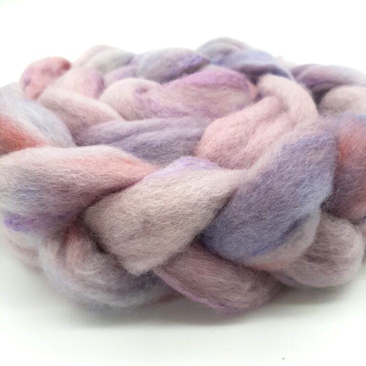 Close up view of a braid of bluefaced leicester and silk fibre hand dyed in shades of purple and blush