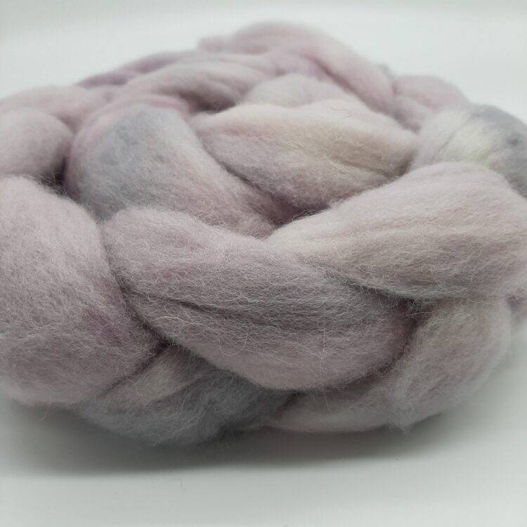 close up view of the side of a braid of hand dyed shetland fibre in pale purple and greys