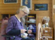 Middle aged white female wearing purple and black spinning yarn on an Ashford Traditional Spinning wheel
