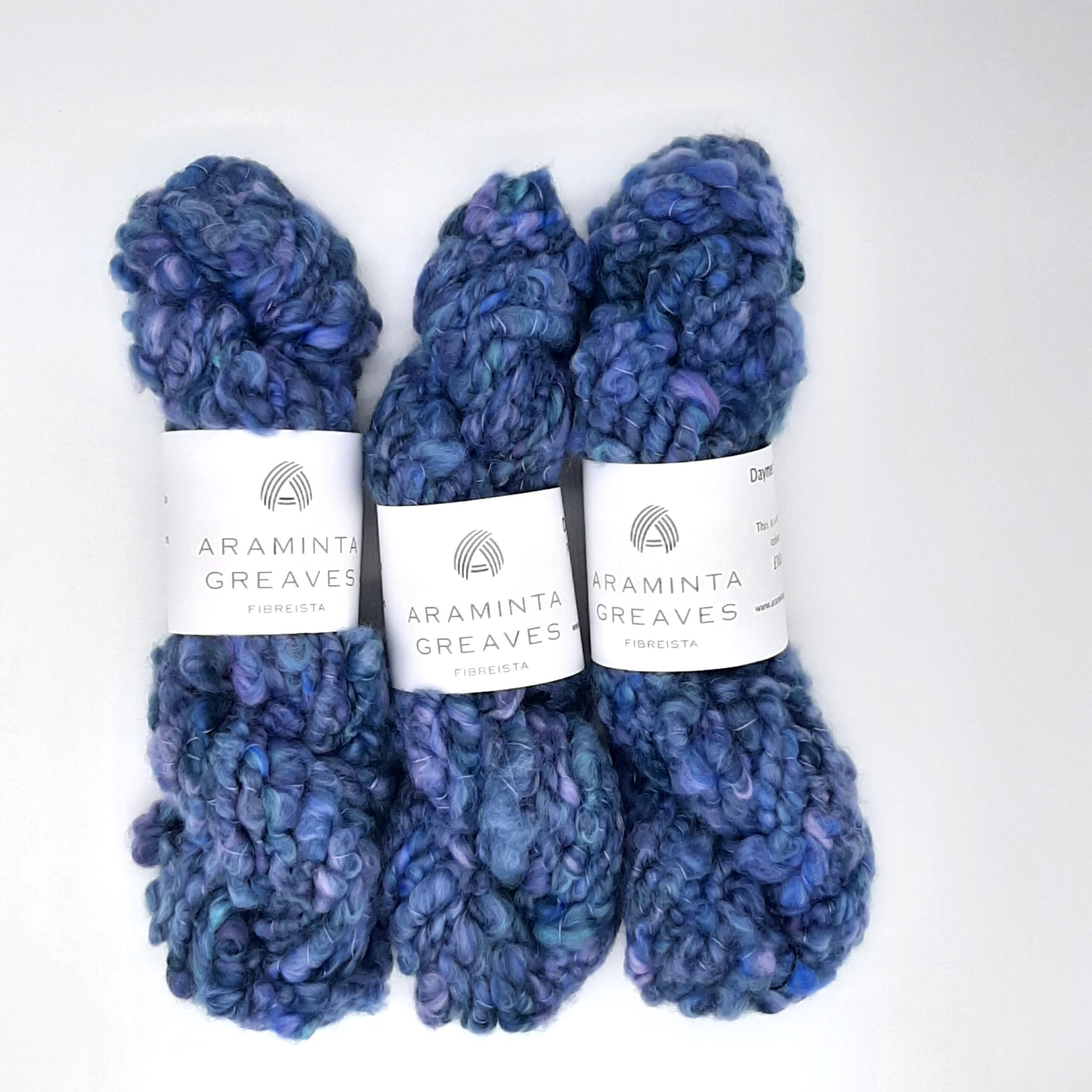 Three skeins of Daymer Storm handspun corespun merino yarn in blues with a hint of lilac.