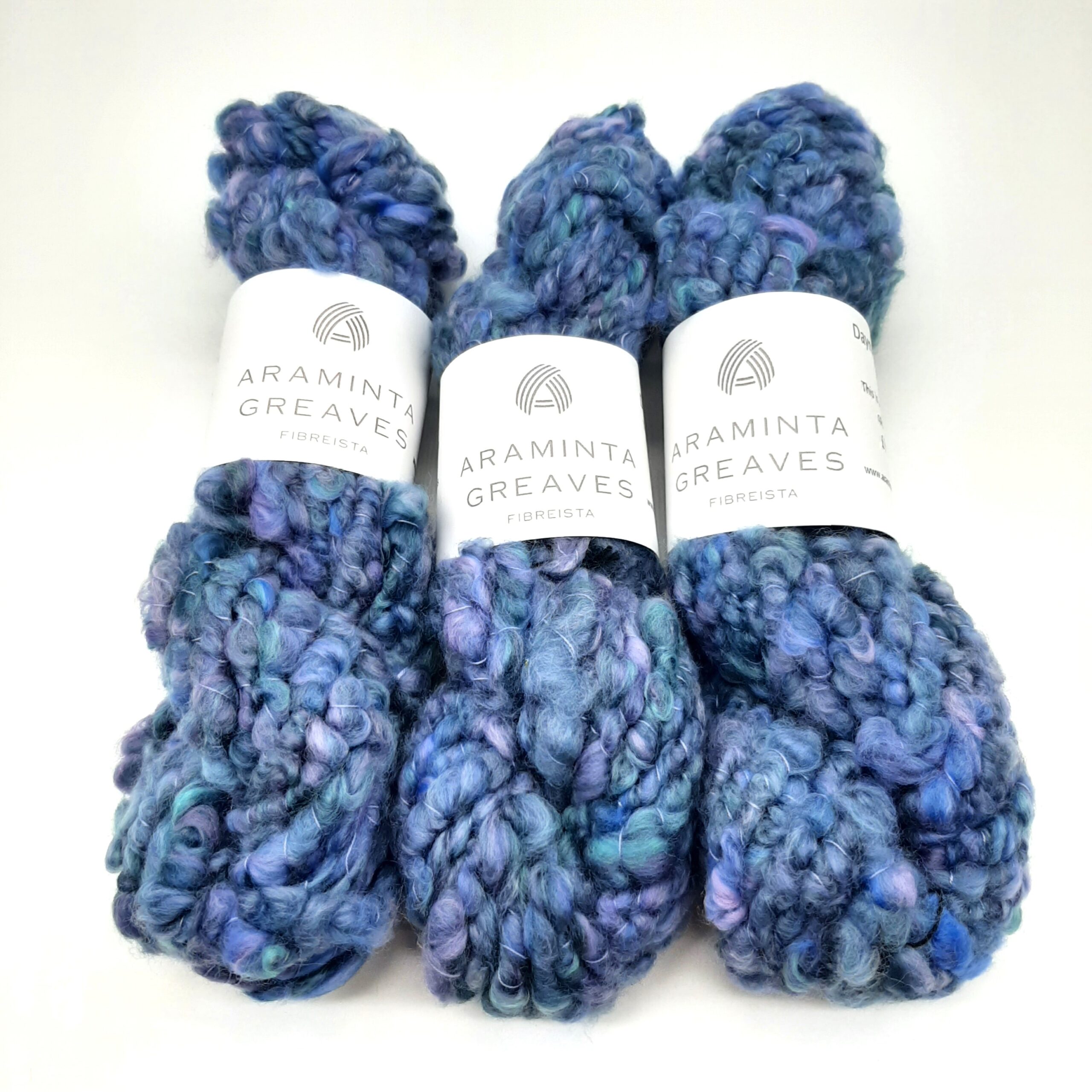 Three skeins of Daymer Storm handspun corespun merino yarn in blues with a hint of lilac.