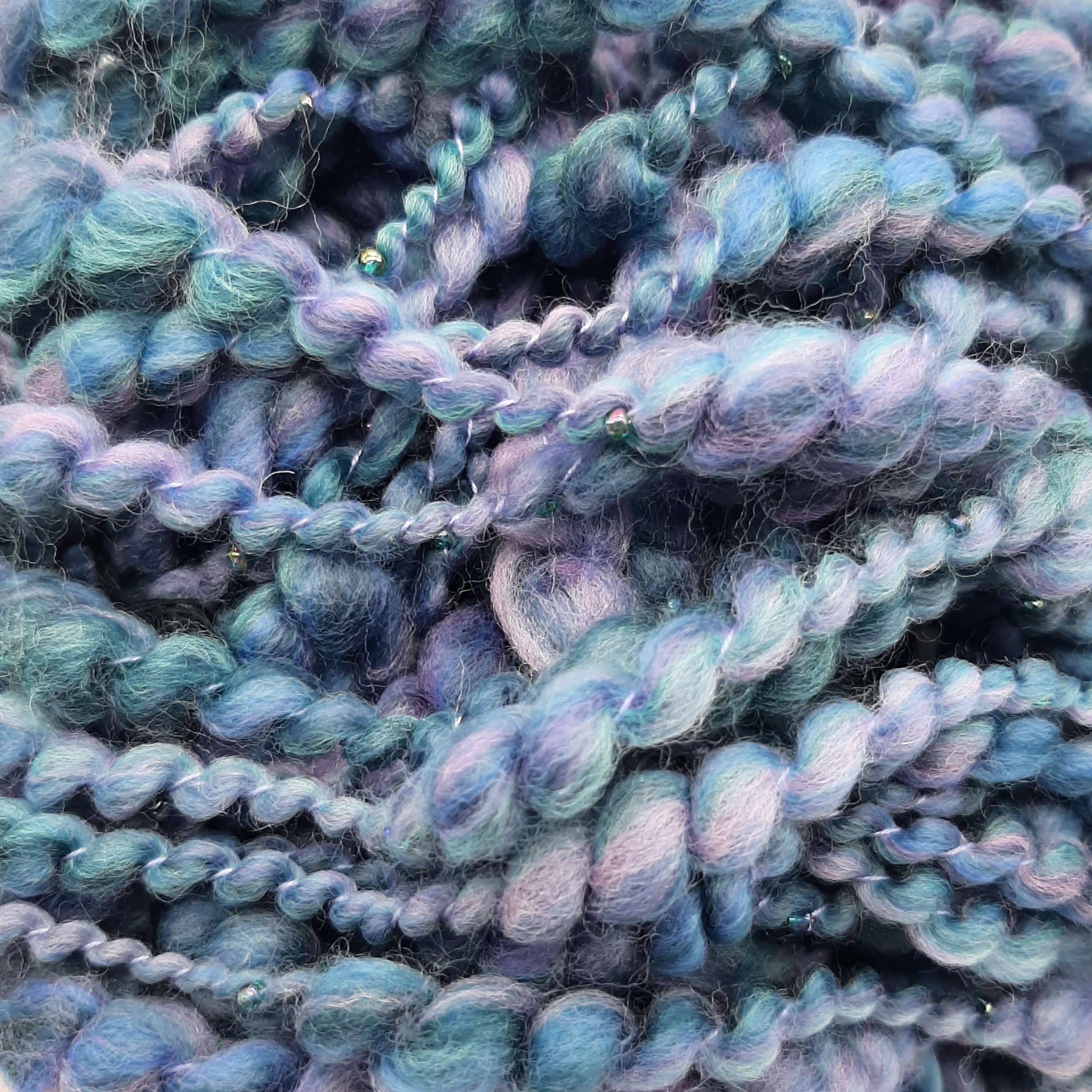 Close up view of Daymer Storm handspun beaded merino yarn in blues with a hint of lilac.
