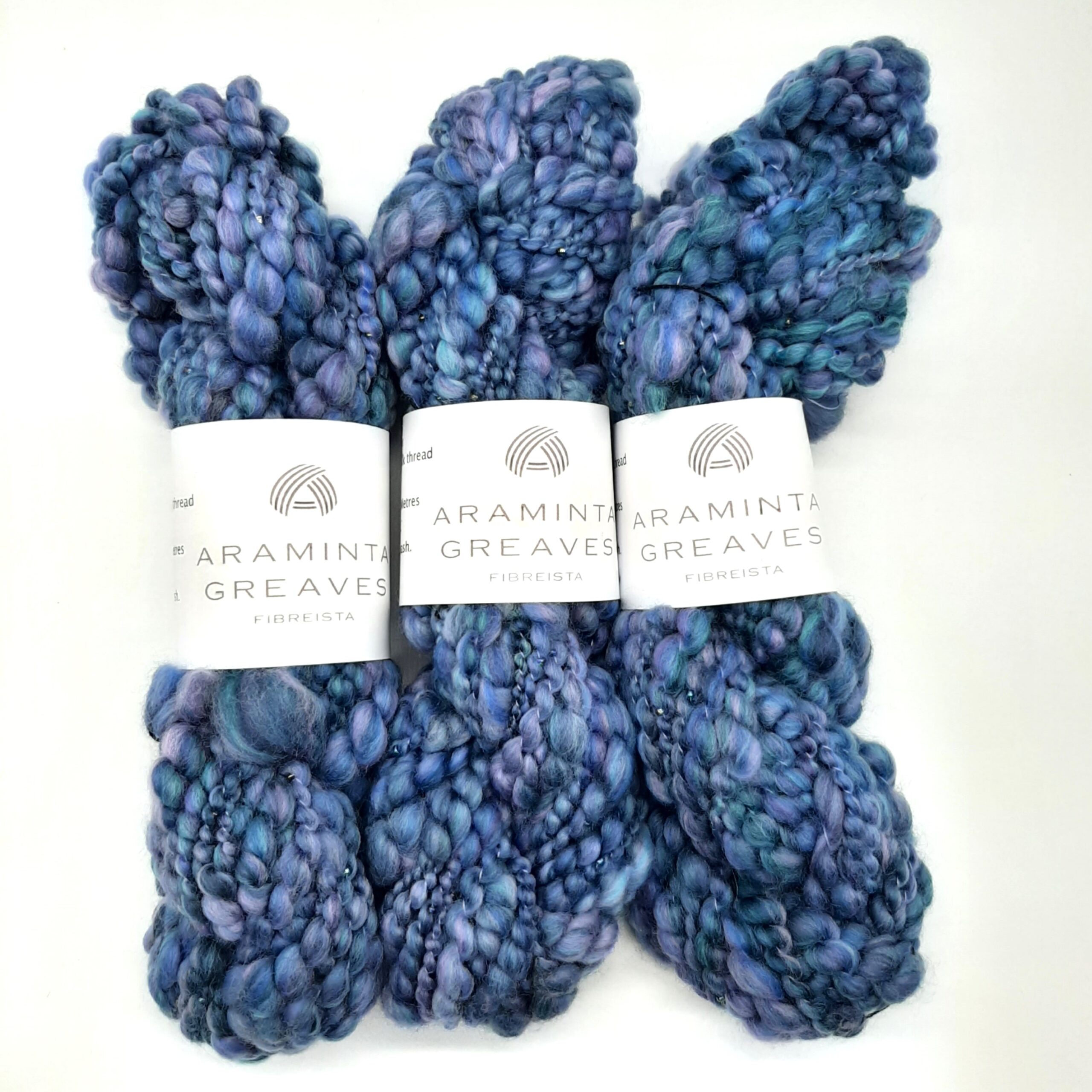Three skeins of Daymer Storm handspun beaded merino yarn in blues with a hint of lilac.