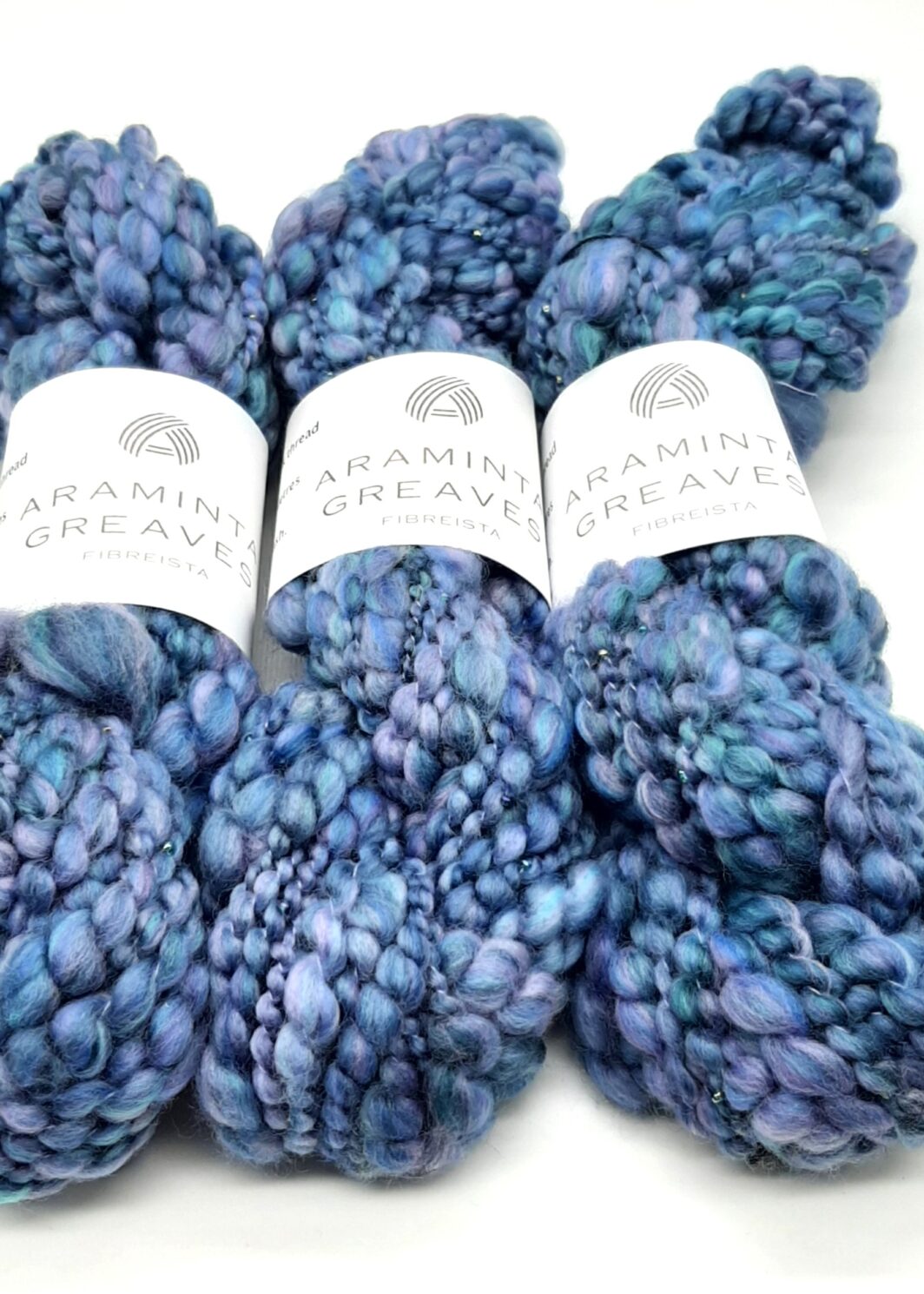 Three skeins of Daymer Storm handspun beaded merino yarn in blues with a hint of lilac.