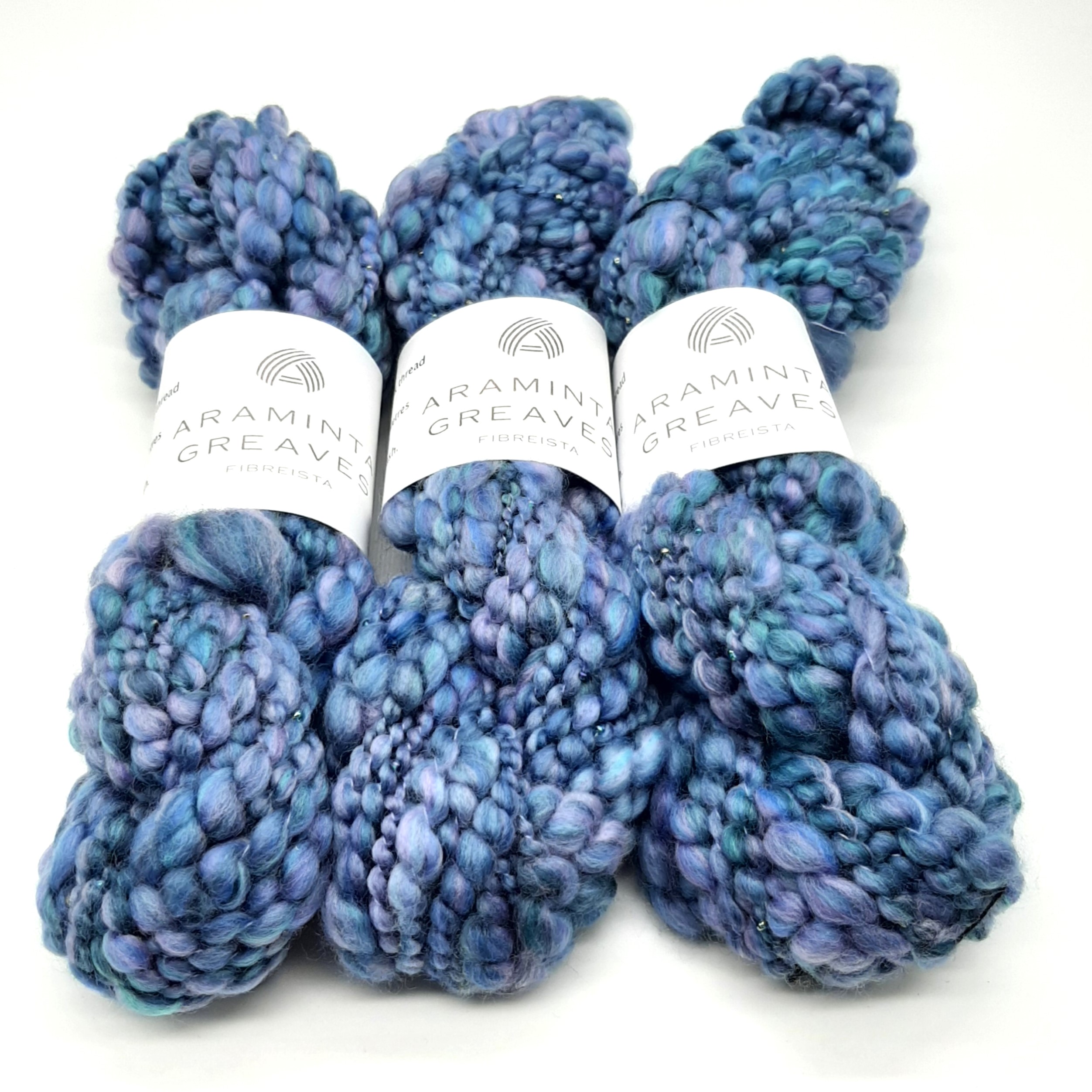 Three skeins of Daymer Storm handspun beaded merino yarn in blues with a hint of lilac.