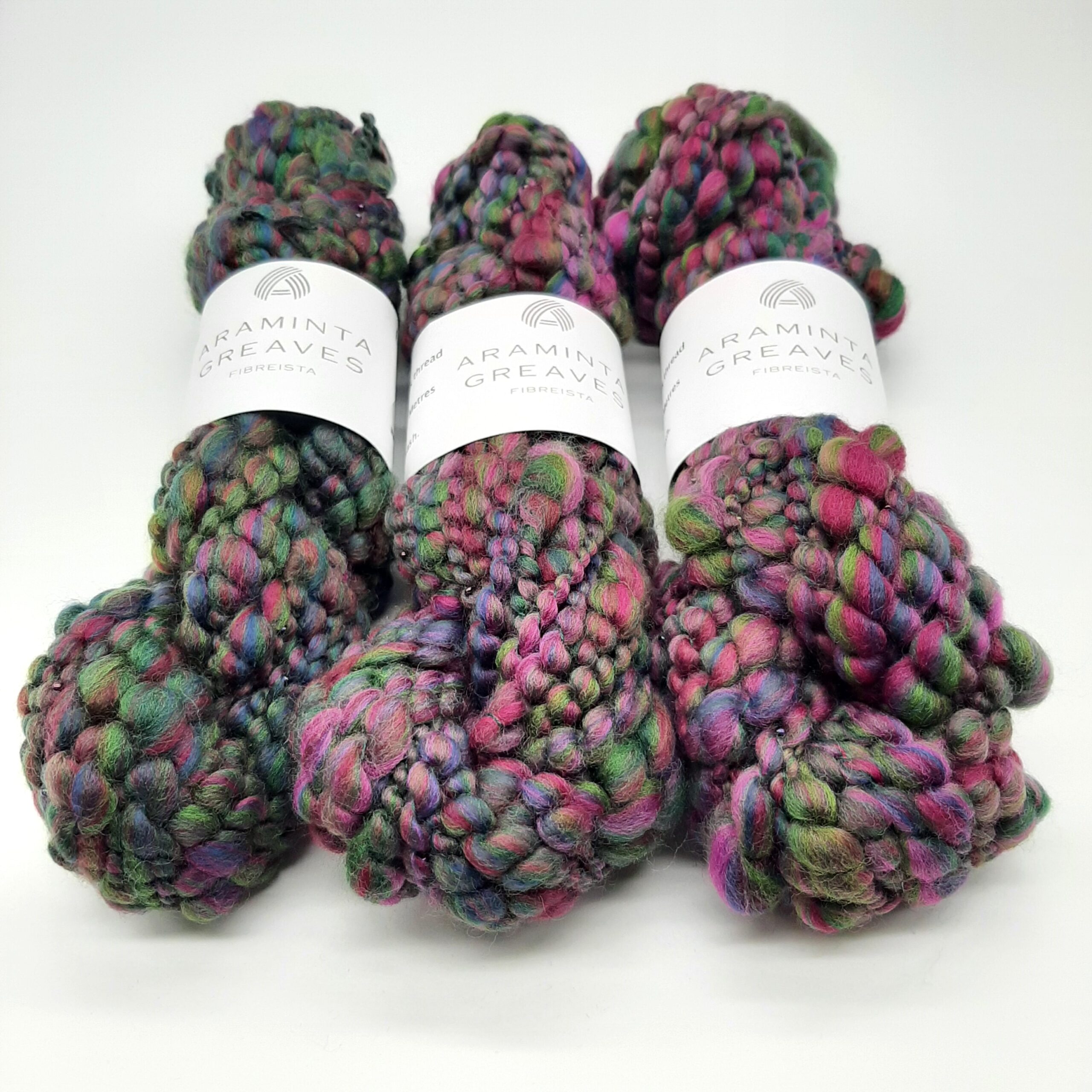 Three skeins of Evening Heather handspun merino beaded yarn in deep, rich heather colours.