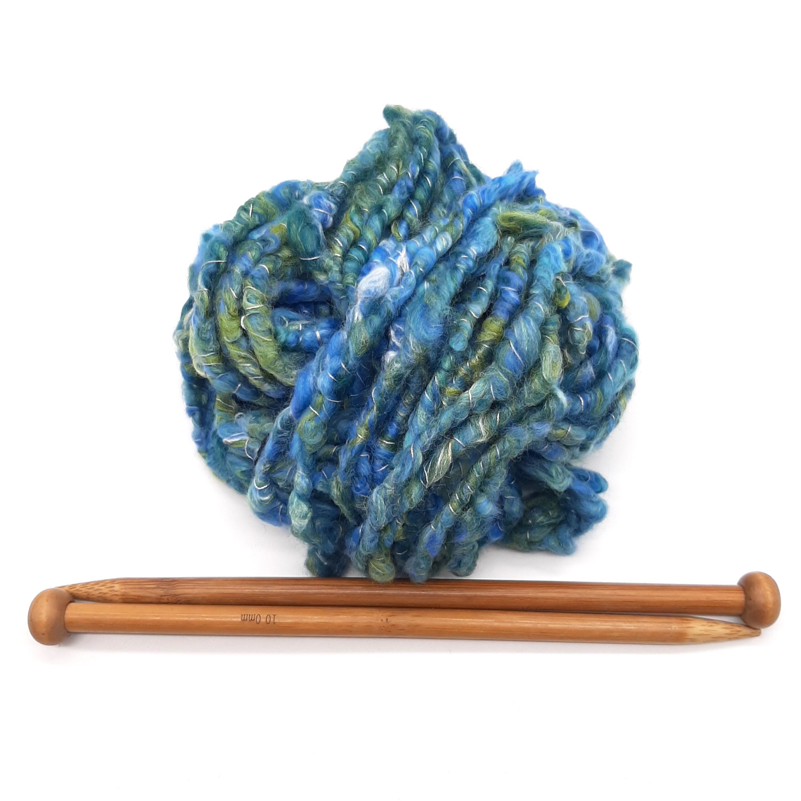 A ball of Polzeath Breeze handspun, corespun merino and silk yarn in blues and greens above a pair of bamboo knitting needles.