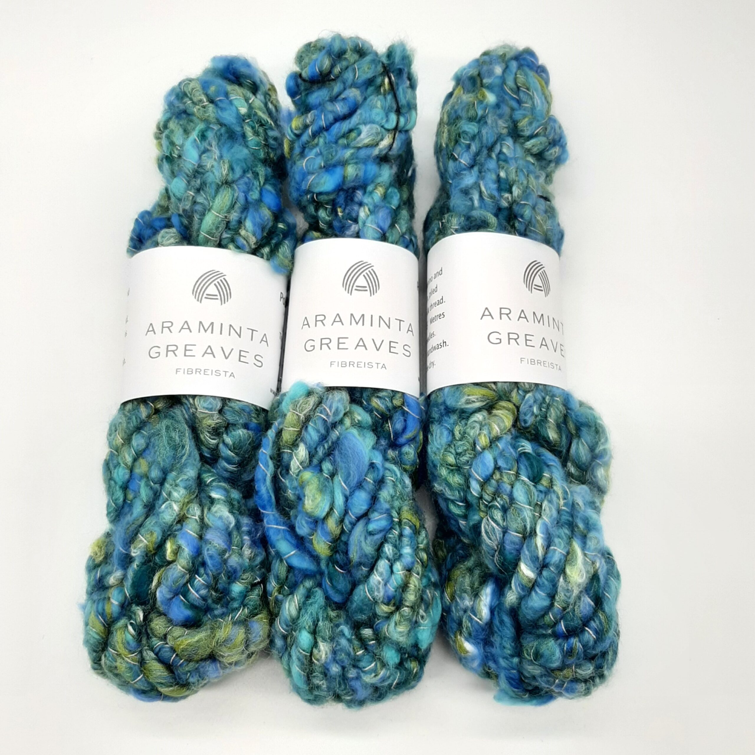 Three skeins of Polzeath Breeze handspun, corespun merino and silk yarn in blues and greens.