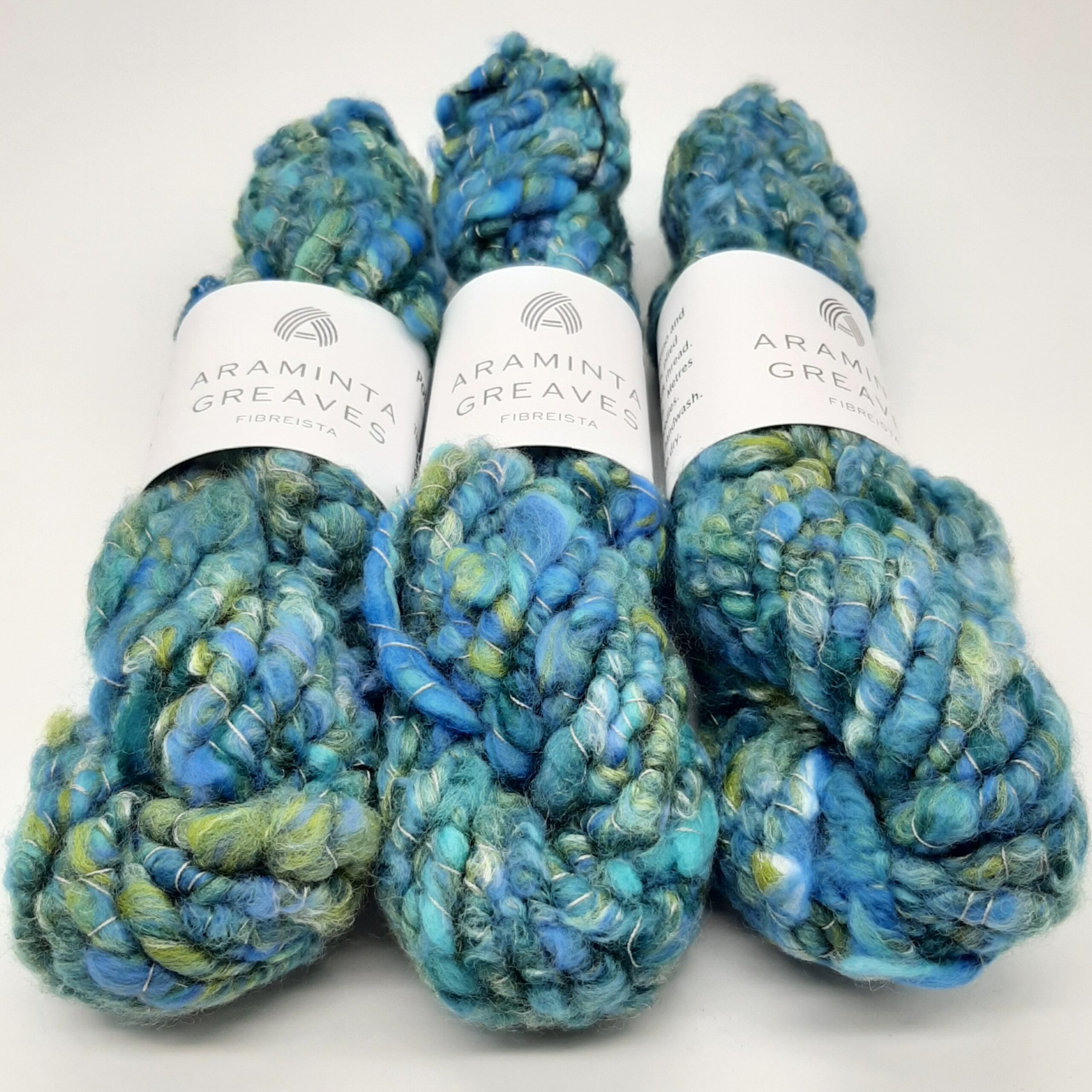 Three skeins of Polzeath Breeze handspun, corespun merino and silk yarn in blues and greens.