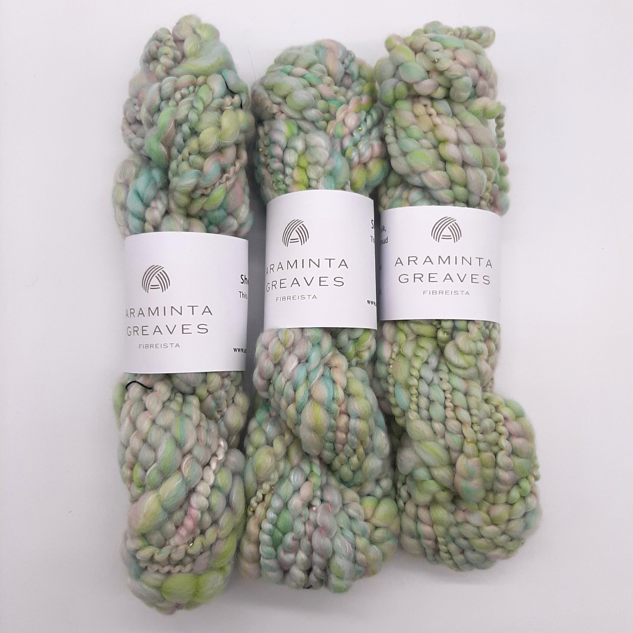 Three skeins of Sherbet Pips handspun, beaded yarn in pastel shades of greens and pinks.