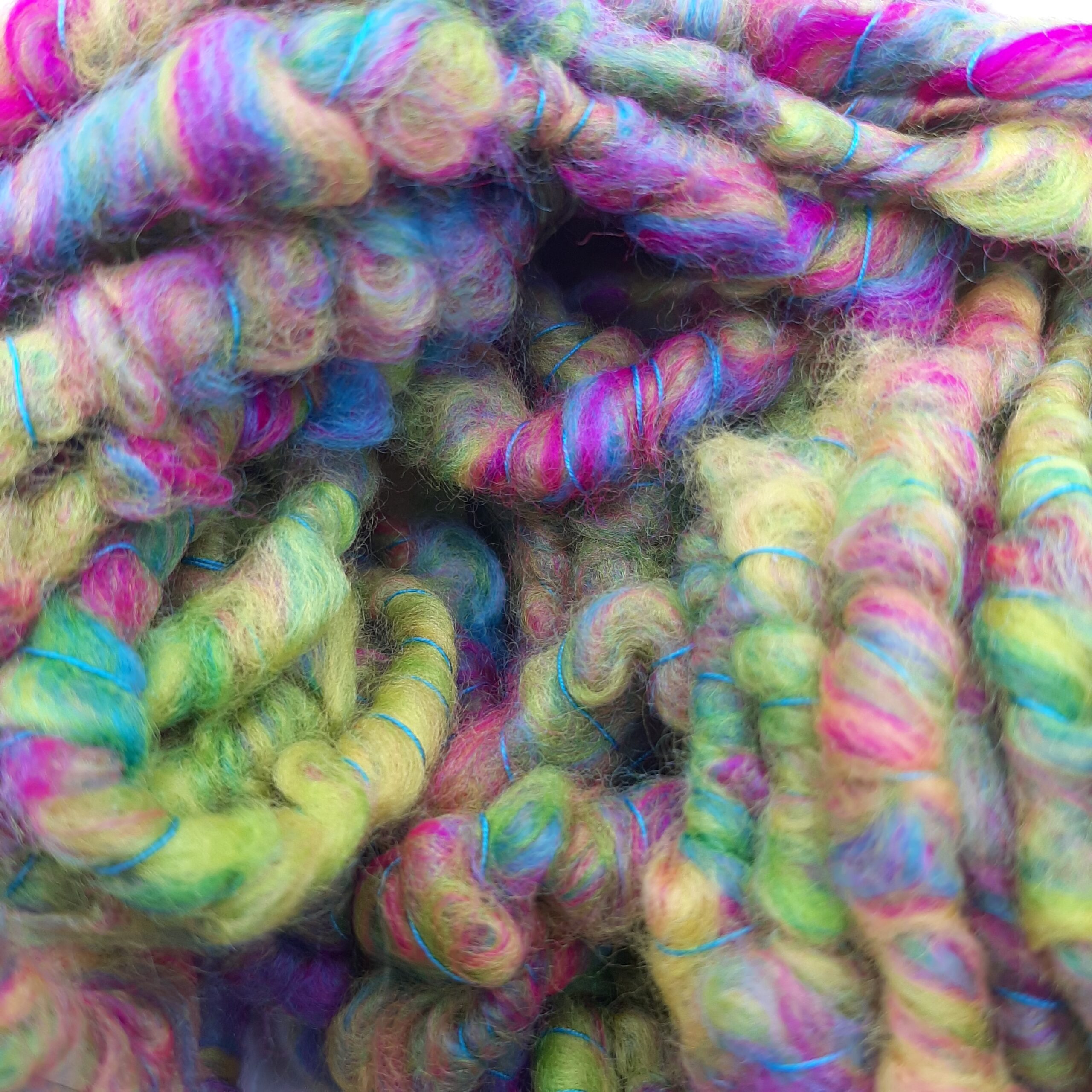 A close up view of Summerleaze Beach Huts hand spun corespun merino yarn in vibrant yellow, pink, green and blue.