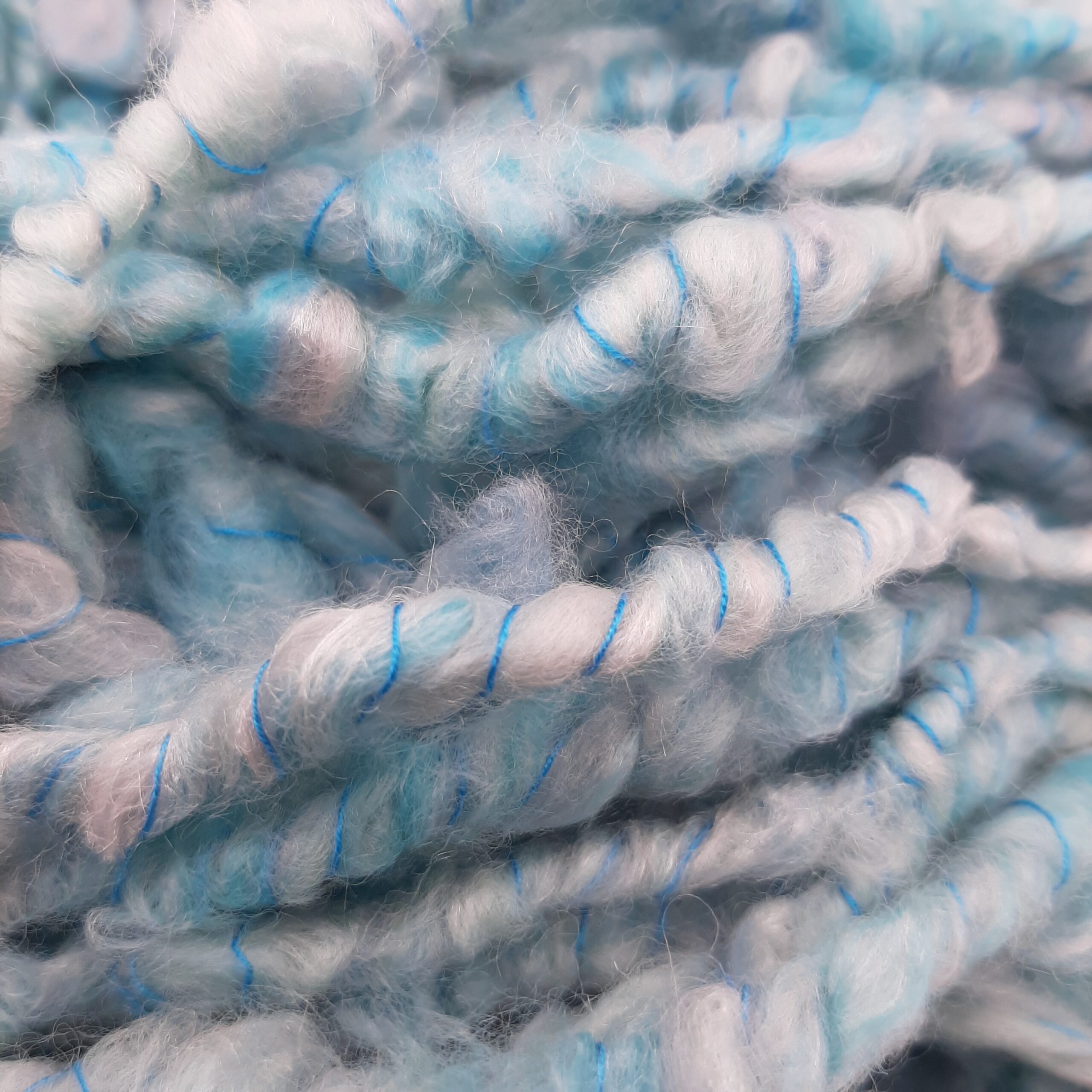A close up of Trevone Foam, handspun corespun merino and silk yarn in pale blue, turquoise and grey.