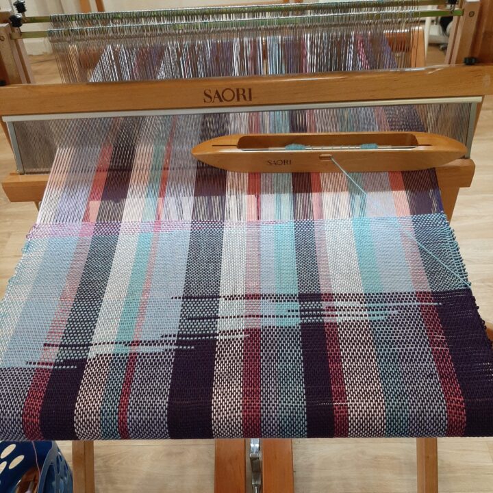 weaving cloth Weaving in shades of purple, pink and blue on the the loom.
