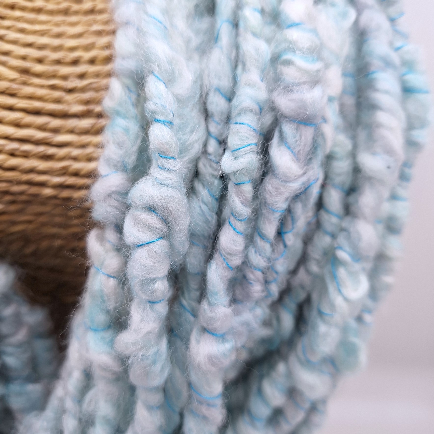 Close up view of handspun merino and silk in pale blues and greys plied with a turquoise Italian silk thread.