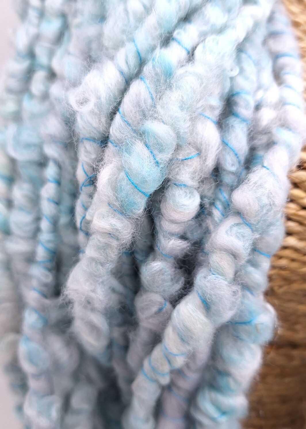Close up view of handspun merino and silk in pale blues and greys plied with a turquoise Italian silk thread.