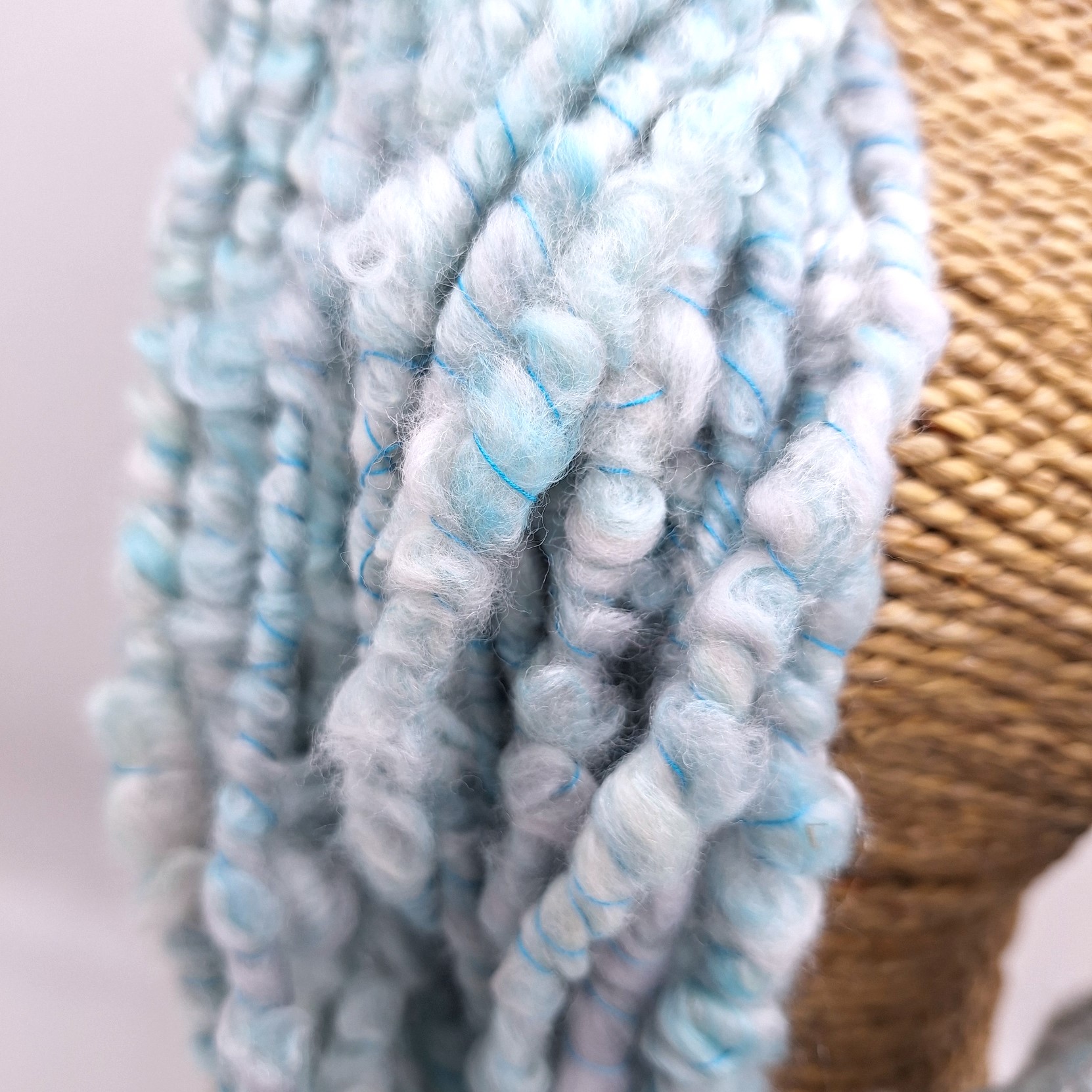 Close up view of handspun merino and silk in pale blues and greys plied with a turquoise Italian silk thread.