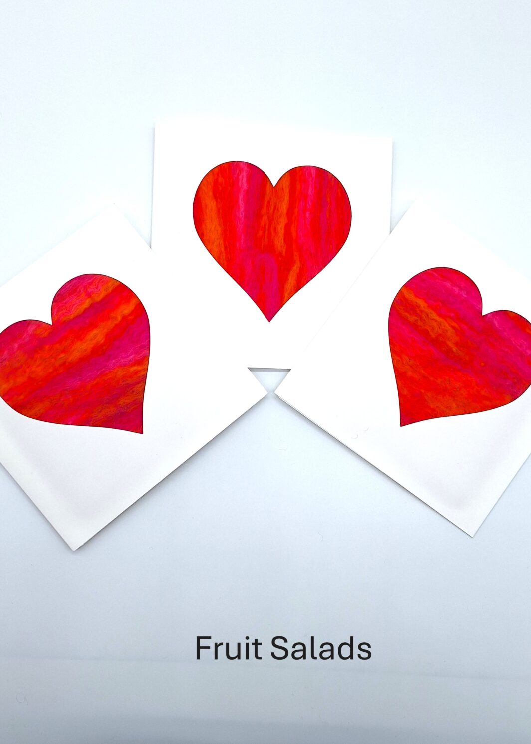 Three white greeting cards with heart shaped apertures filled with bright orange and pink merino handmade felt in my Fruit Salads colourway. Made by Araminta Greaves Fibreista