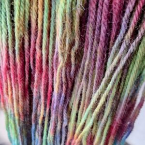 close up view of yarn dyed in shades of green, pink, purple and blue