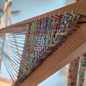 close up view of the beginning of a continuous strand weaving on an enormous triloom.