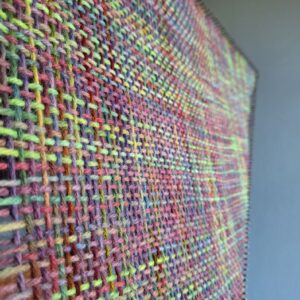 Sideways view of a multicoloured weaving by Araminta Greaves Fibreista on an enormous triloom