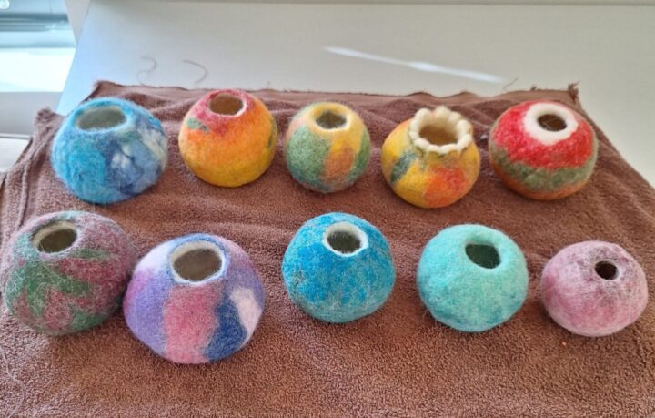 Araminta Greaves Fibreista wet felt vessel workshop Colourful spherical felt vessels in two rows on a brown towel.